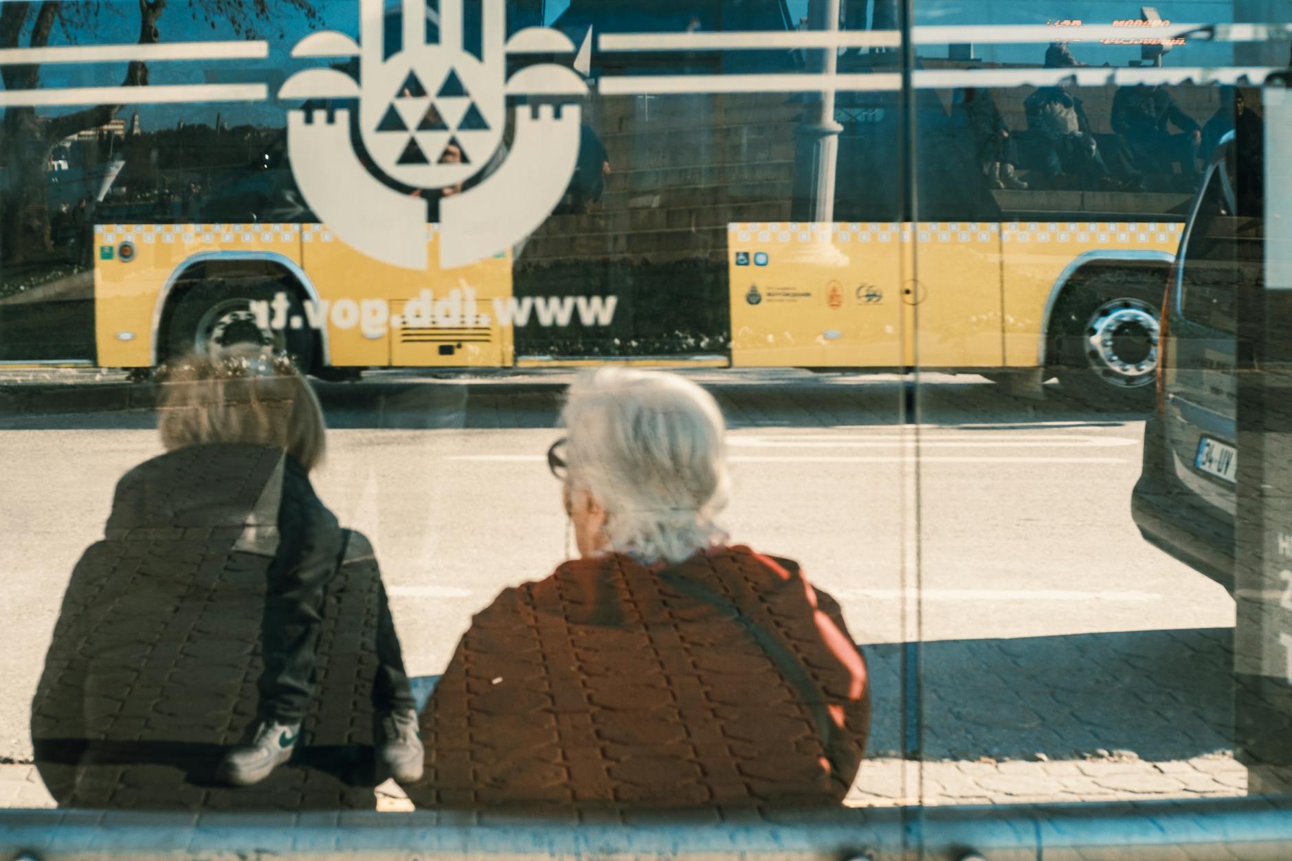 Dwie osoby na przystanku autobusowym w mieście przy żółtym autobusie