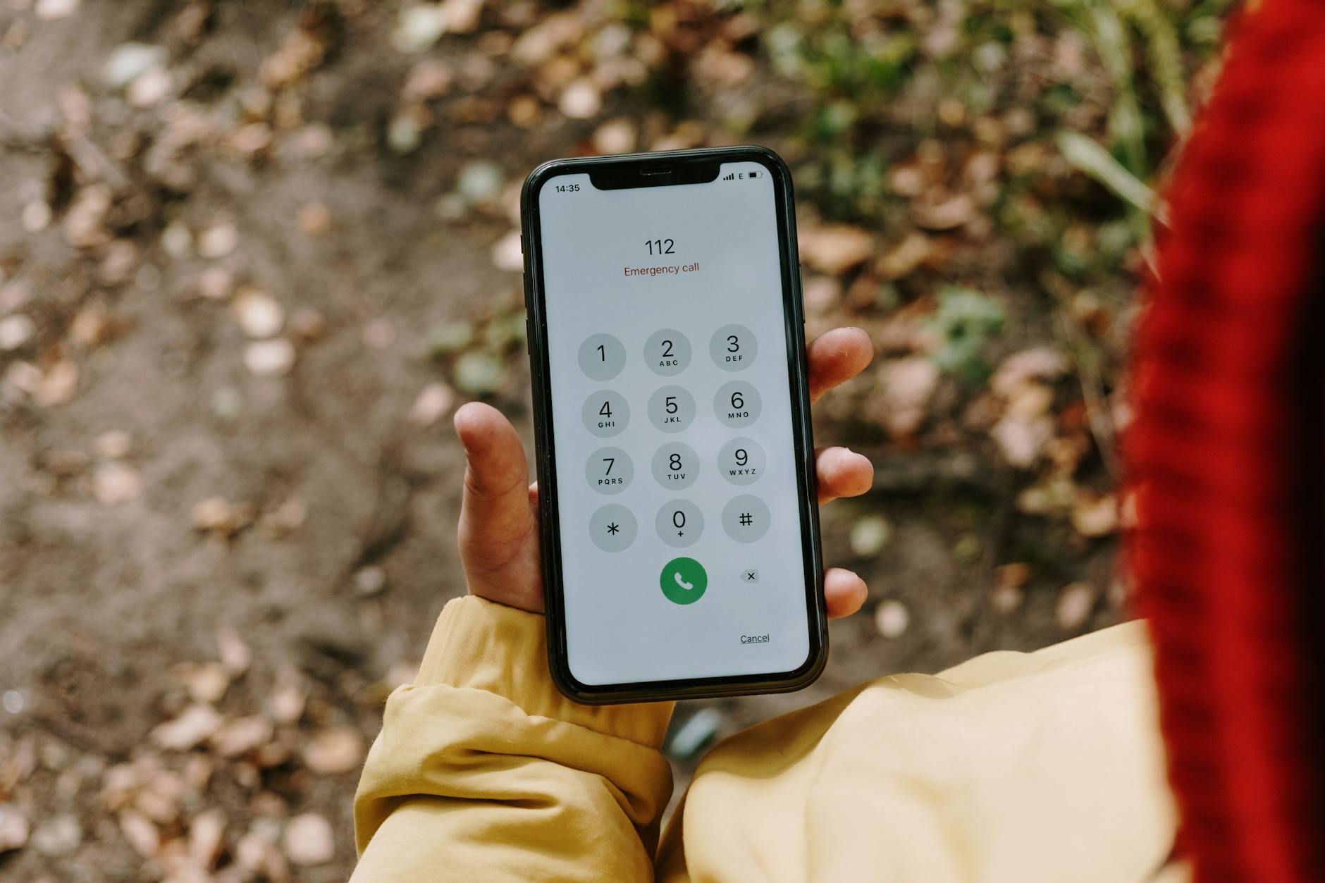 Jak przygotować mieszkanie pod kątem szybkiego alarmowania Numery przy telefonie i widoczne oznaczenia adresu Smartfon na dworze z wyświetlonym numerem alarmowym 112