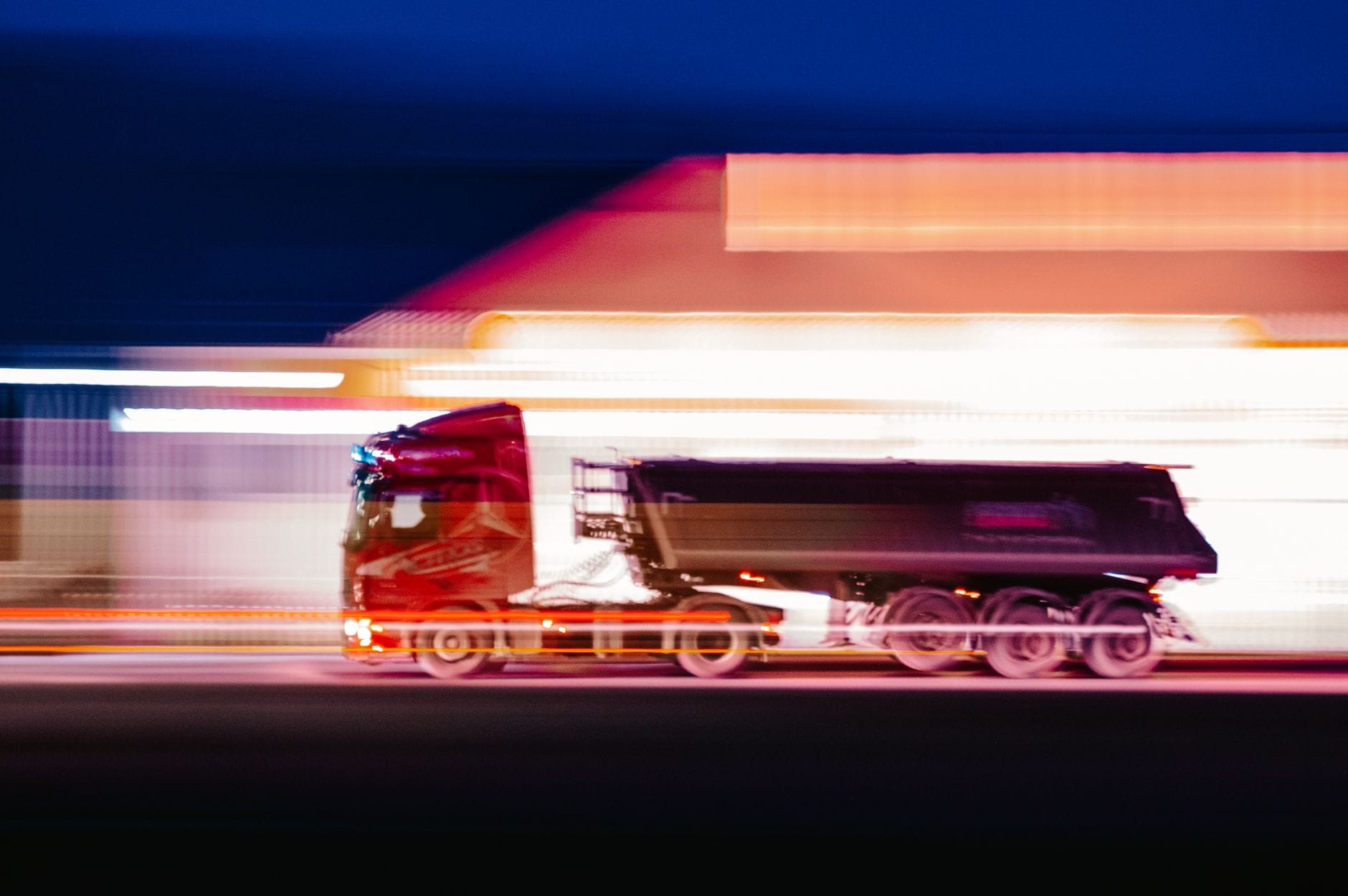 Rozmazany w ruchu tir pędzący nocą przez oświetlone miasto