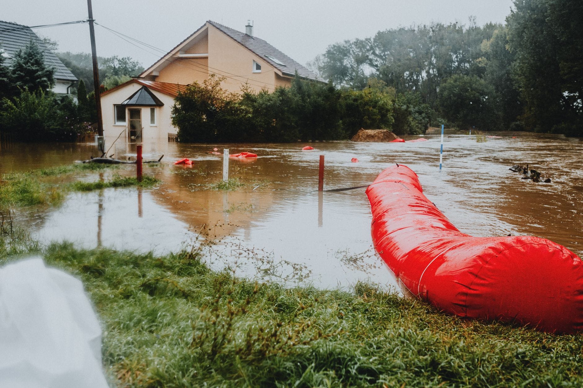 Dom w Wejherowie a podtopienia – proste sposoby ochrony piwnicy i parteru Zalana ulica przy domach zabezpieczonych czerwonymi zaporami przeciwpowodziowymi